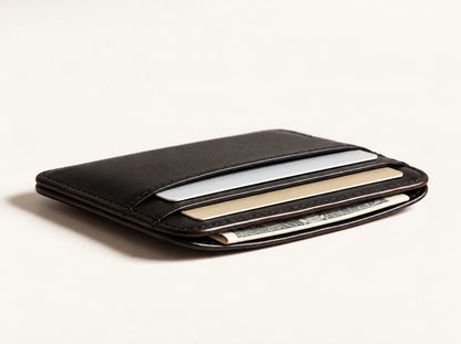 The Essential Wallet in black leather, holding cards and a folded note
